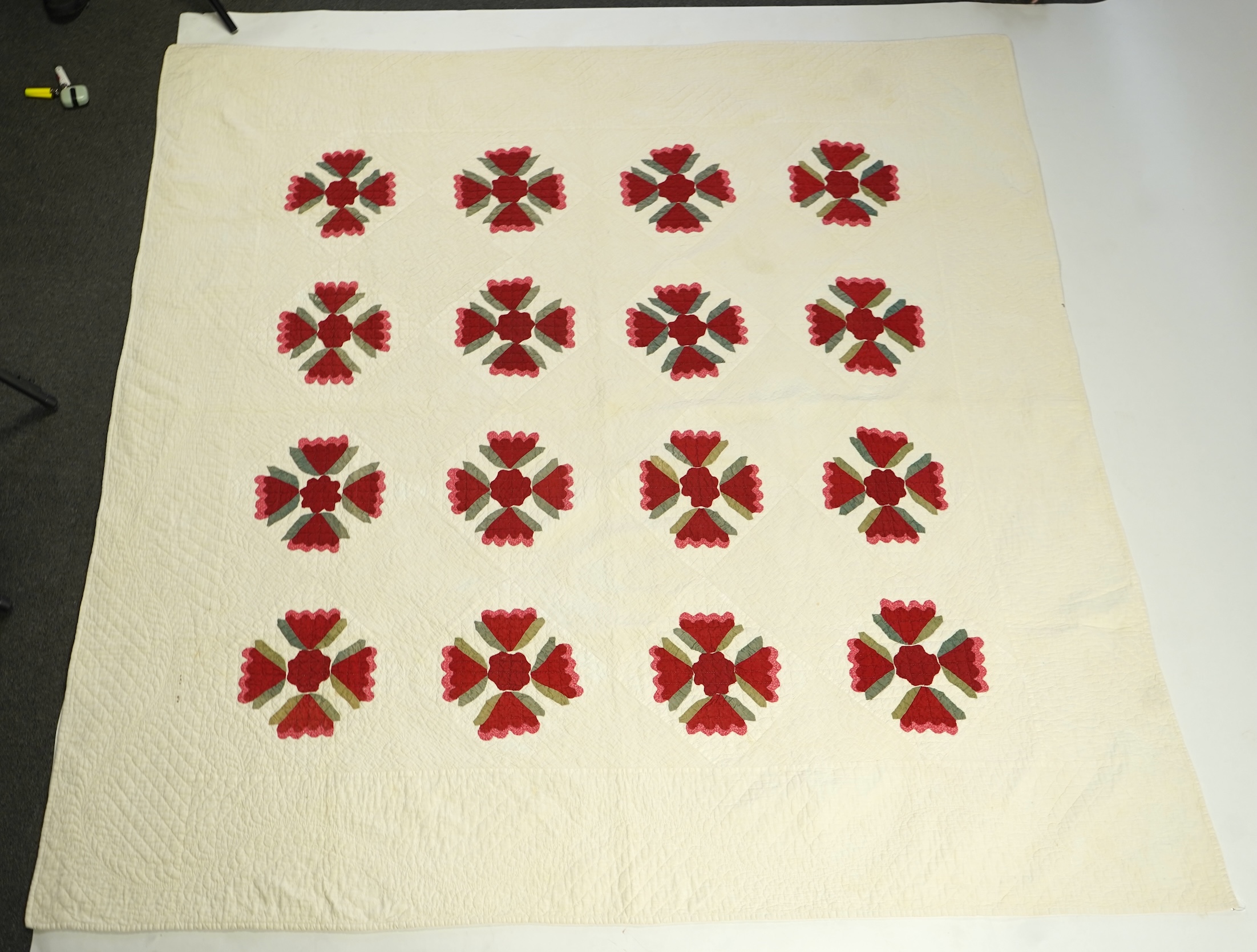 An American quilt from Kentucky, circa 1900. Intricately hand quilted on a white ground, appliquéd with stylistic repeating floral motifs in strong red and green cottons, all hand pieced. This quilt is a fine example of